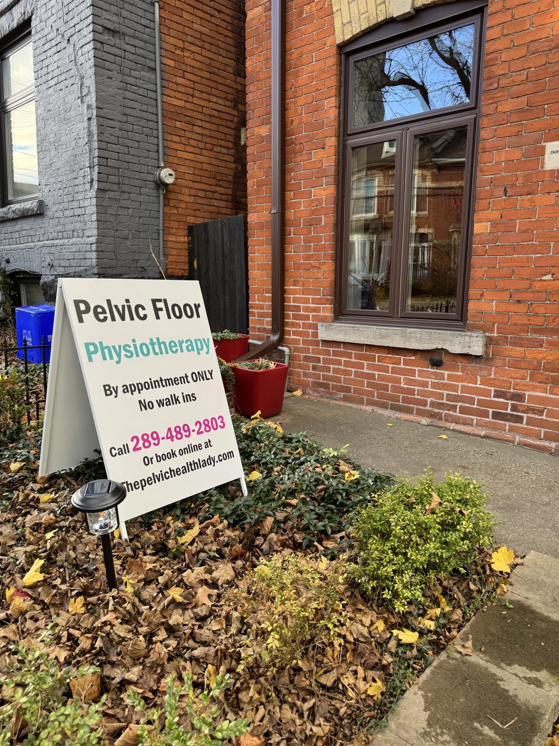 Sandwich board sign outside the Hamilton clinic reading Pelvic Floor Physiotherapy, by appointment only